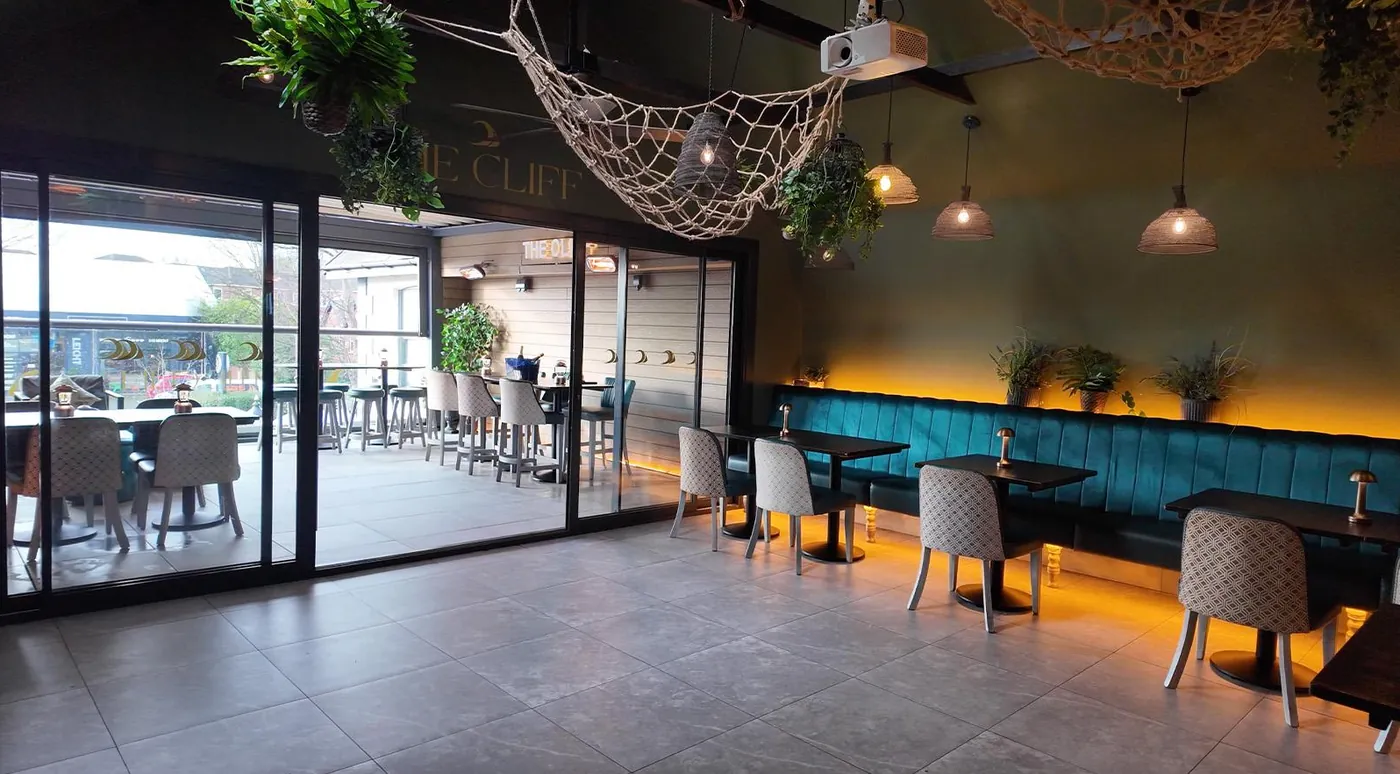 The Cliff in the evening, amber lights under the velvet banquettes and glass doors open to the rooftop